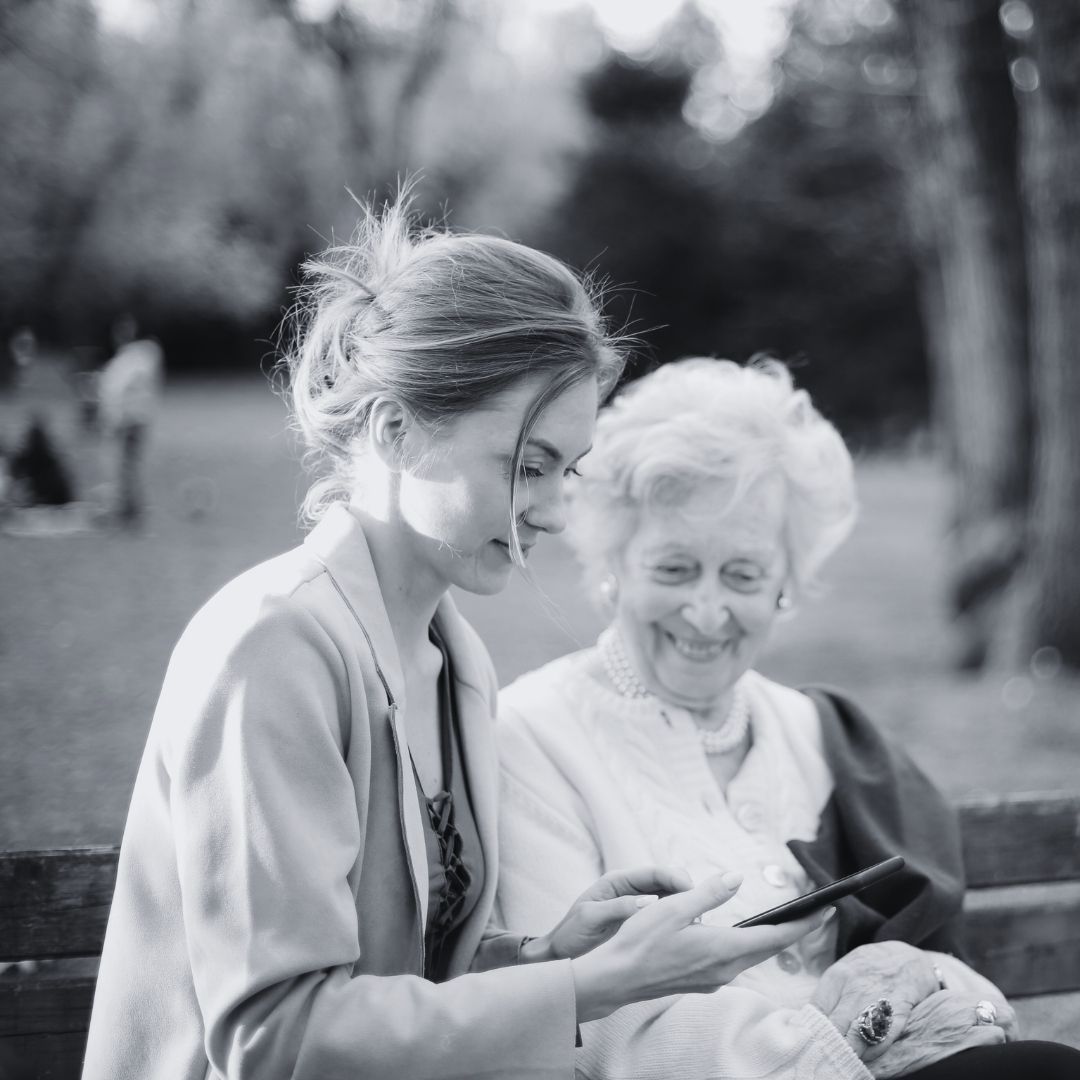 worker showing elderly woman a photo on phone 