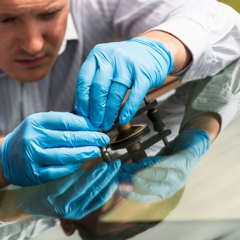 an auto glass expert works on a car windshield