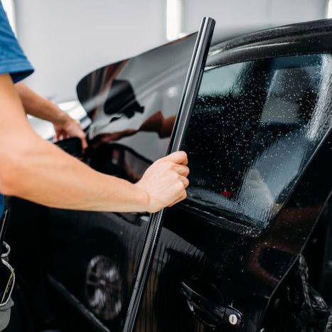 A person adding tint to a car window