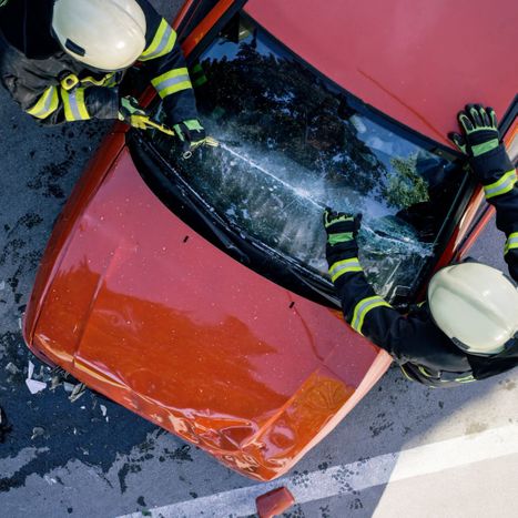 firefighters cutting through the windshield of a car that has been in an accident