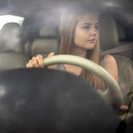 young woman looking through windshield