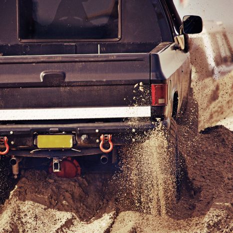 a truck powering through a sand pit