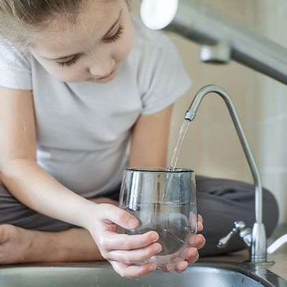 little girl looking closely at pouring water