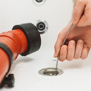 Plumber snaking a clogged drain