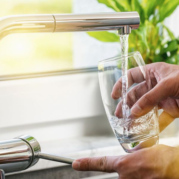 person filling a glass from the sink