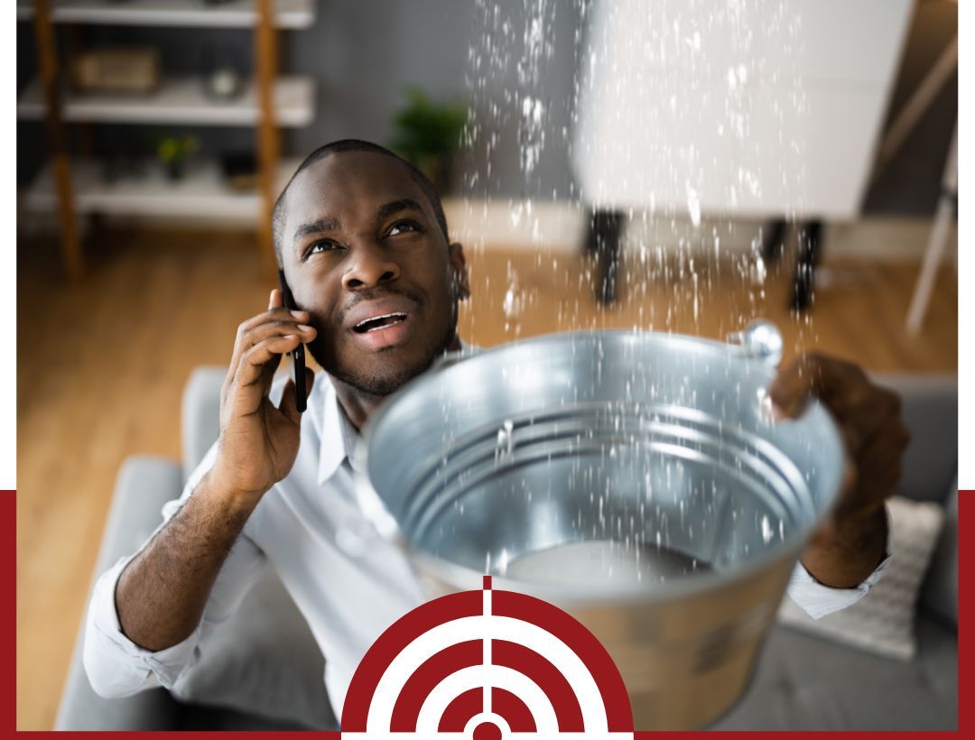 A man on the phone while catching leaking water in a bucket