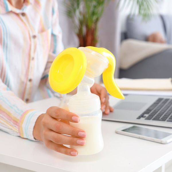 Hand holding a portable manual breast pump in an outdoor setting Hand holding a portable manual breast pump in an outdoor setting