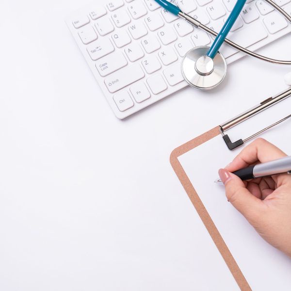 Healthcare professional writing something on a clipboard. 