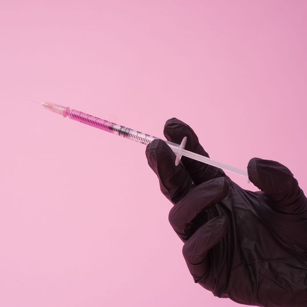 gloved hand holding syringe 