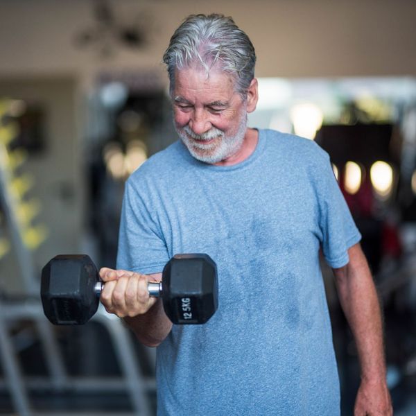 Man lifting weights with a dumbbell and looking down.