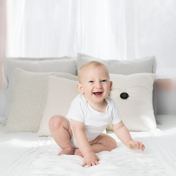 happy baby sitting on bed