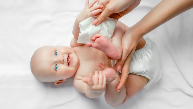 mother cleaning baby with wipe