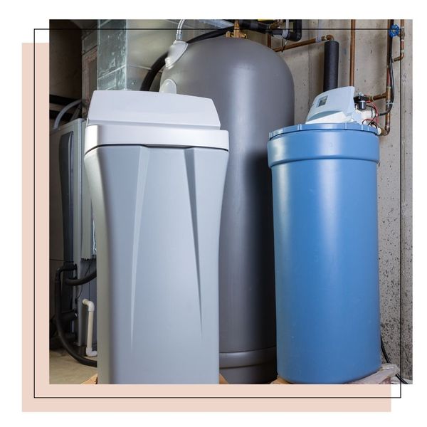 Old and new water softener tanks in a utility room waiting for replacement to remove minerals from hard water