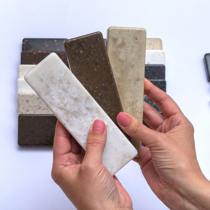 Person holding a variety of countertop samples in their hands. 