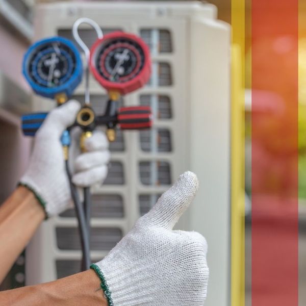 Close-up of a technician's hands in white gloves holding HVAC manifold gauges near an outdoor air conditioner, while giving a confident thumbs-up sign. centennial2.jpg