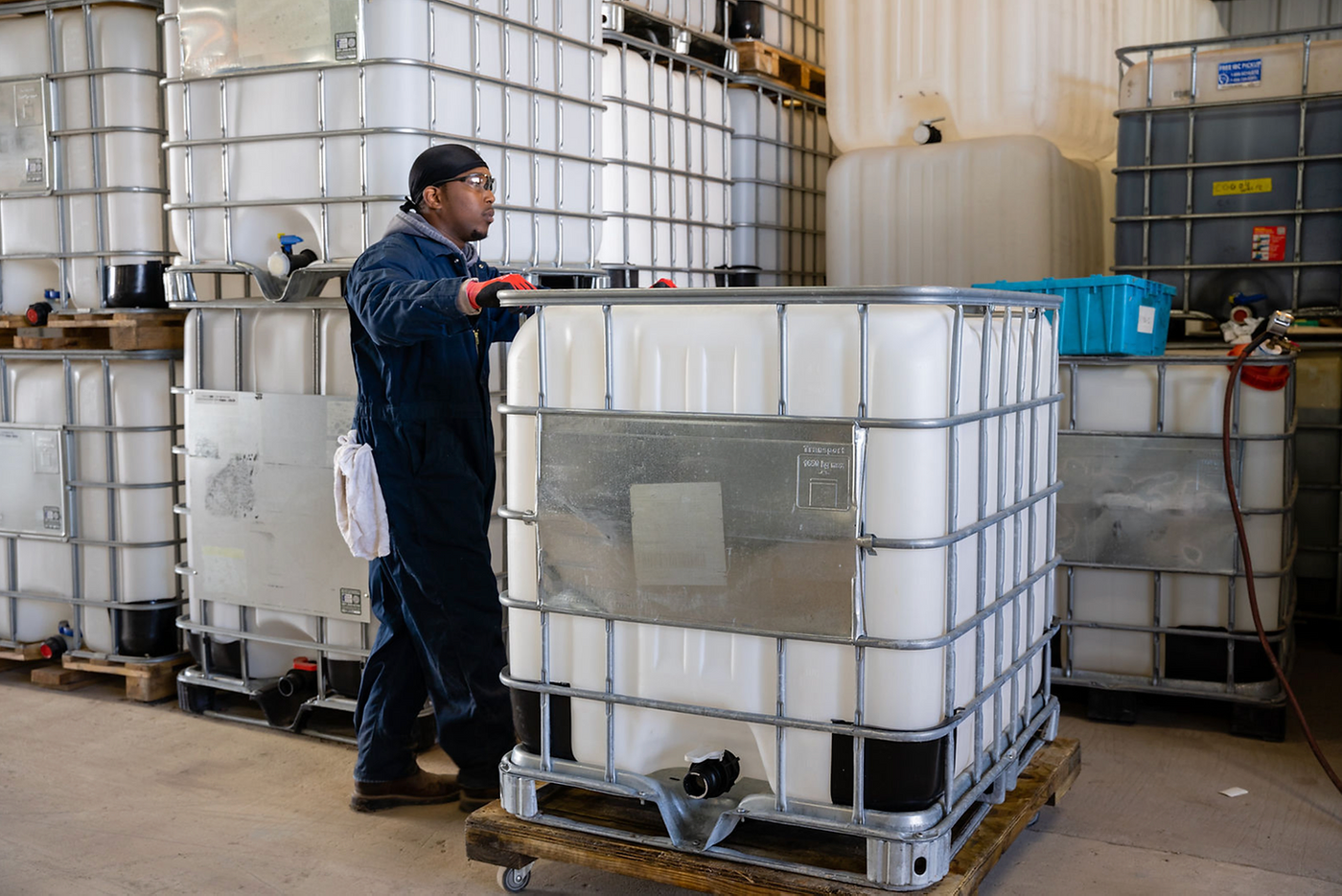 Man moving a large poly IBC tote in a warehouse