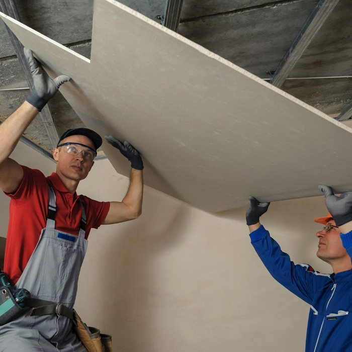 Two men placing a ceiling sheetrock 