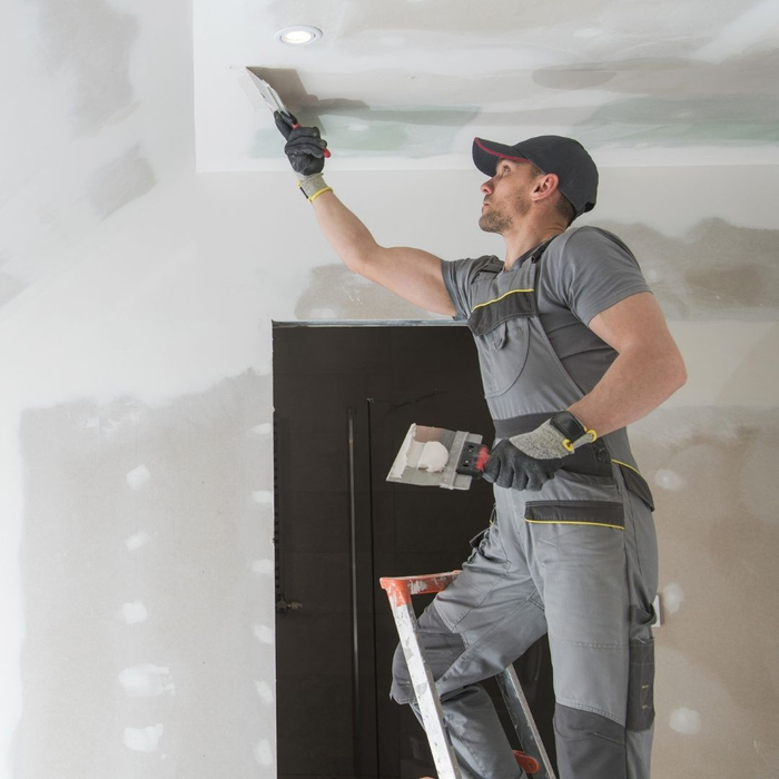 Man repairing ceiling with drywall 
