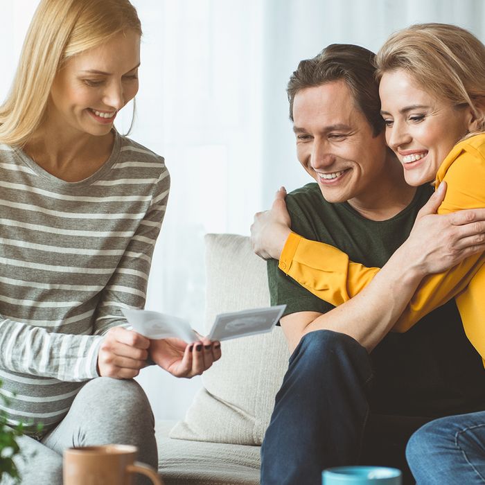 Image of a couple showing ultrasound images to a friend