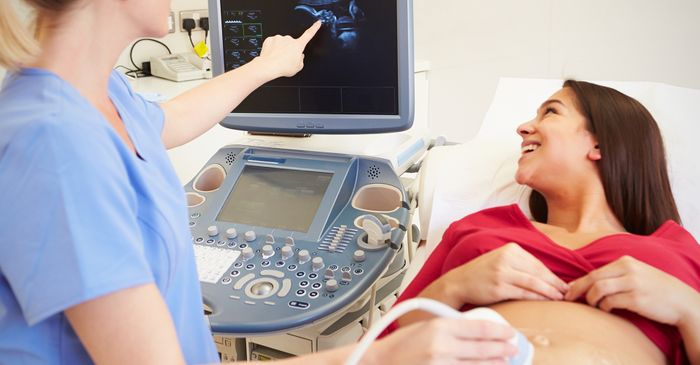 A pregnant woman smiles seeing the ultrasound image on a computer screen