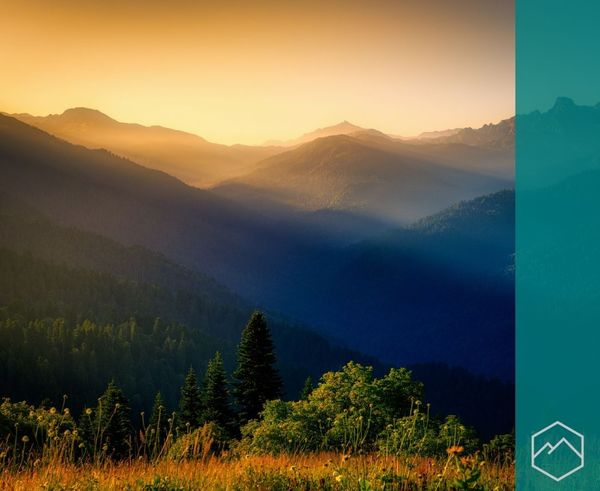 A scenic view of rolling hills and mountains at sunset with light filtering through the valleys. A scenic view of rolling hills and mountains at sunset with light filtering through the valleys.