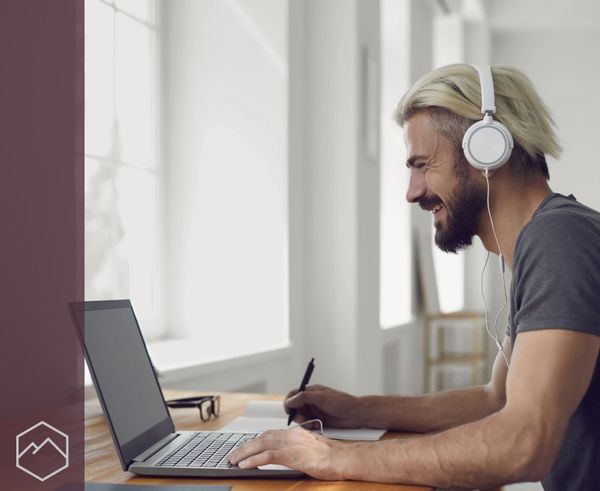 smiling man wearing headphones and using a laptop to make a telehealth call. smiling man wearing headphones and using a laptop to make a telehealth call.