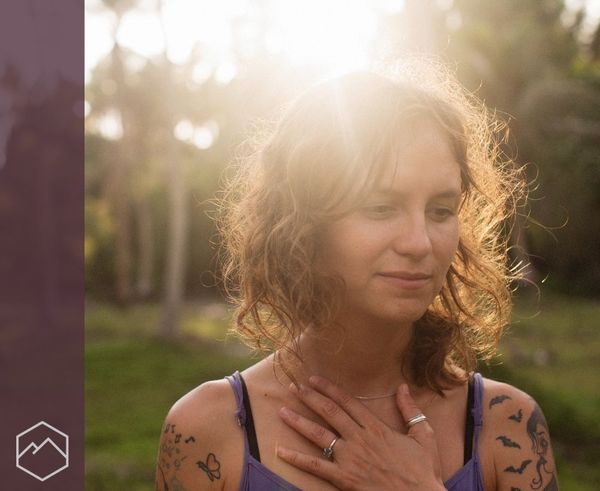 A woman smiling softly in a sunlit forest placing her hand on her chest in relief. A woman smiling softly in a sunlit forest placing her hand on her chest in relief.