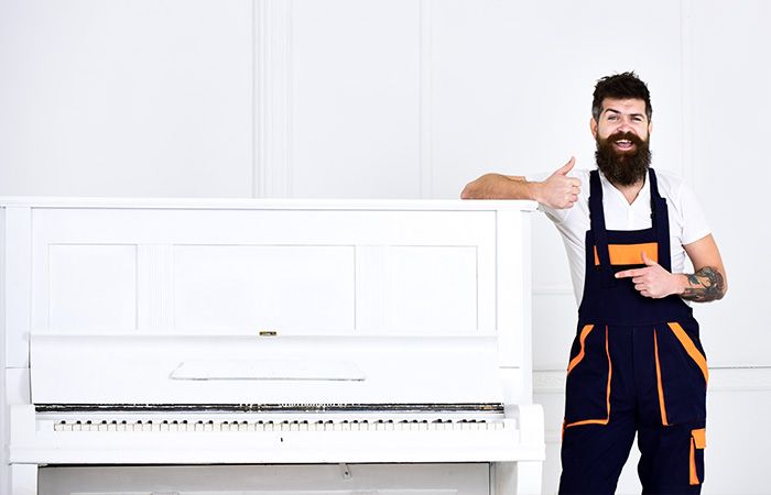 man doing thumbs up by piano