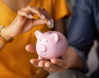 couple inserting money into a piggy bank