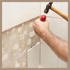 person removing bathroom tiles