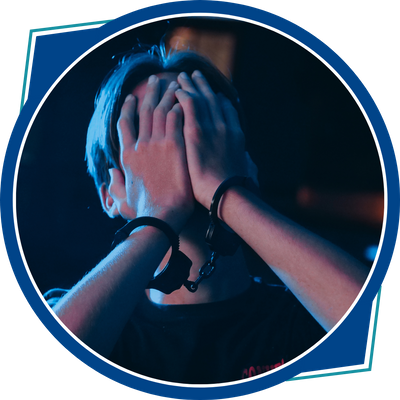 young person with handcuffs and hands over face in anguish