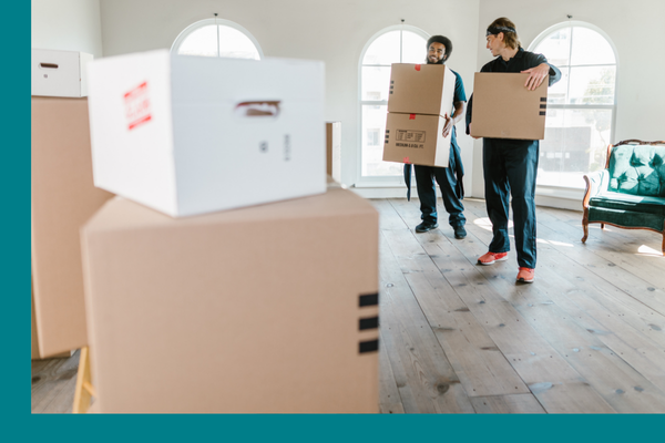 Two movers stacking boxes inside of a home