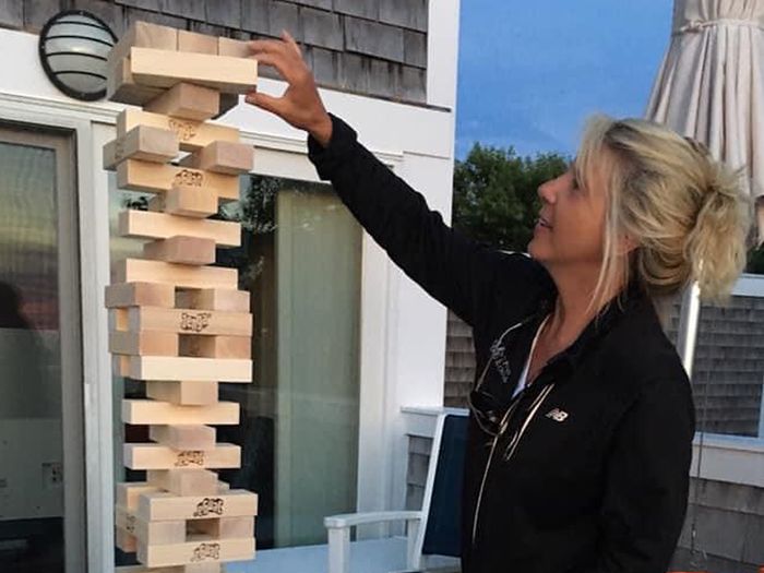 Liisa Holm placing a block on top of a very tall Jenga tower