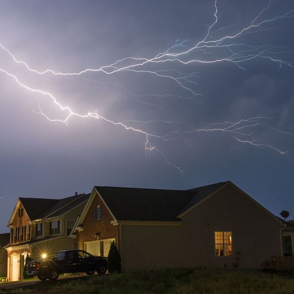 Lightning striking above a home