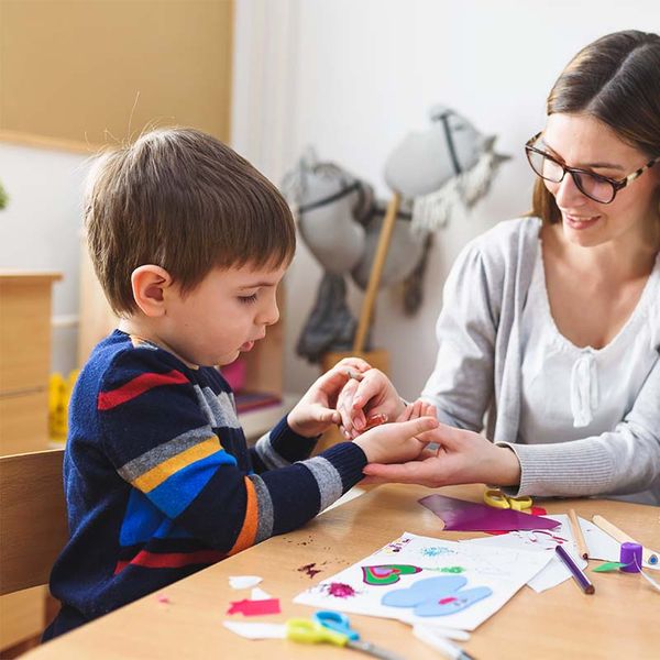 child and daycare worker working on crafts