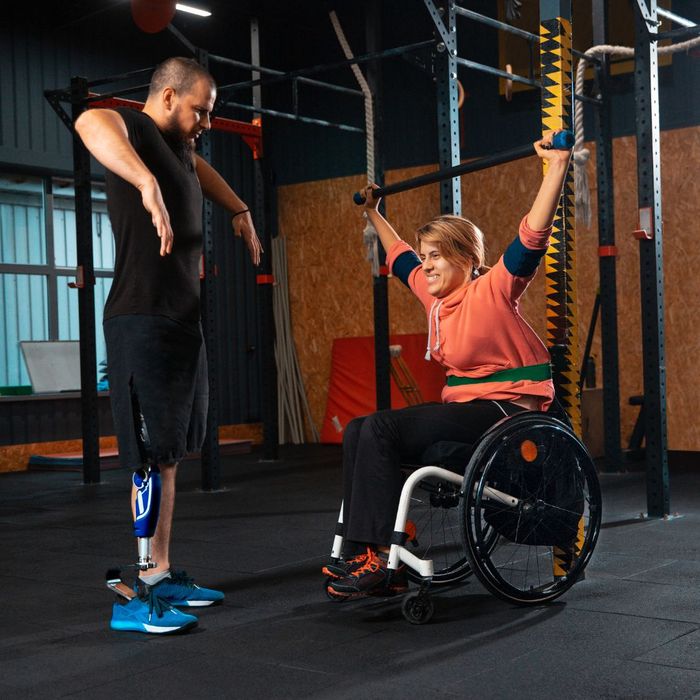 a man doing personal fitness training to a woman in a wheelchair