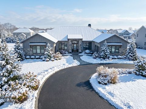 A wide, high-angle view of a large suburban home with a perfectly cleared black asphalt driveway following a heavy Long Island snowfall.
