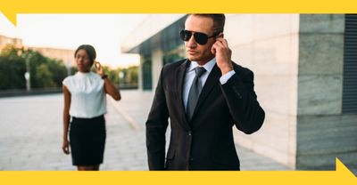 A close protection officer monitors the surroundings while escorting a corporate executive.