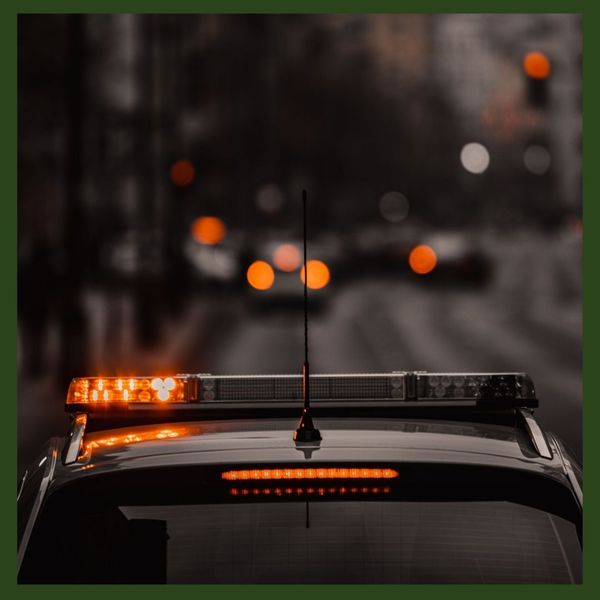 Patrol Car with Siren Lights on Driving Down Road