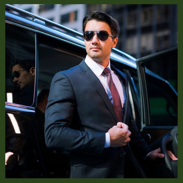 An executive security professional stands ready next to a secure black luxury vehicle.