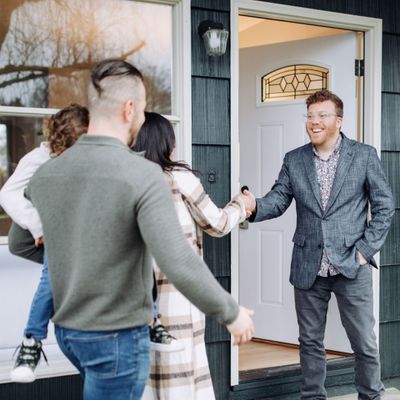 Real estate agent shaking hands with family at home