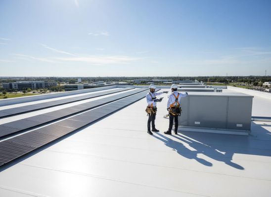 Technicians Inspecting Solar Panels and HVAC on Commercial Rooftop