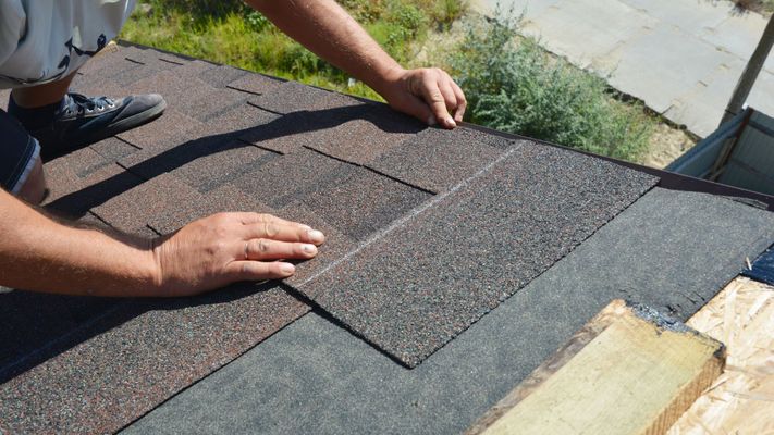 Roofer putting shingles on a house. 