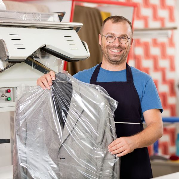 smiling worker holding dry cleaning