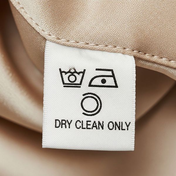 A close-up of a care tag with iron and dry clean symbols. A close-up of a care tag with iron and dry clean symbols.