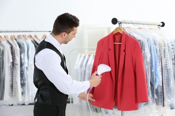 Man dry cleaning a red blazer. 