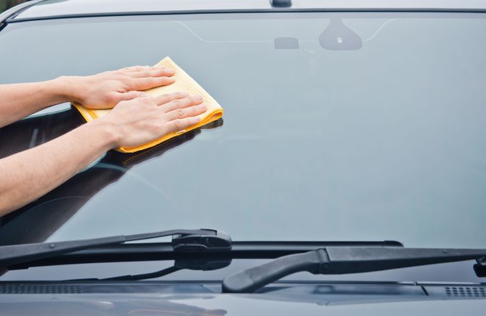Person wiping a windshield with a microfiber cloth