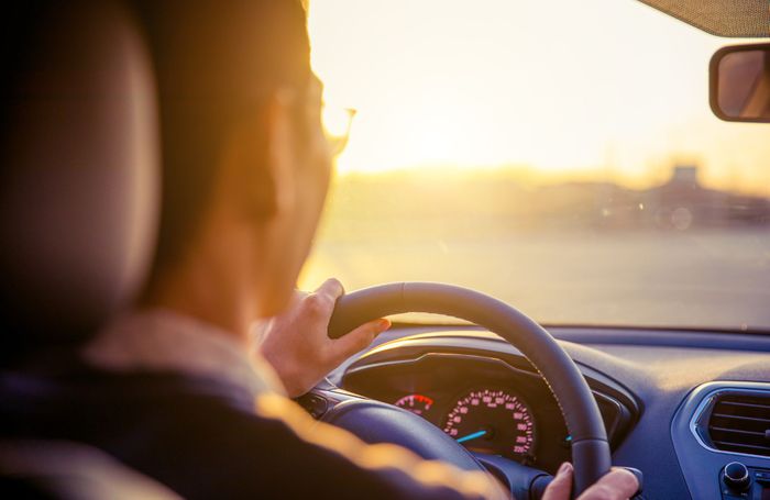 Person driving a car at sunset