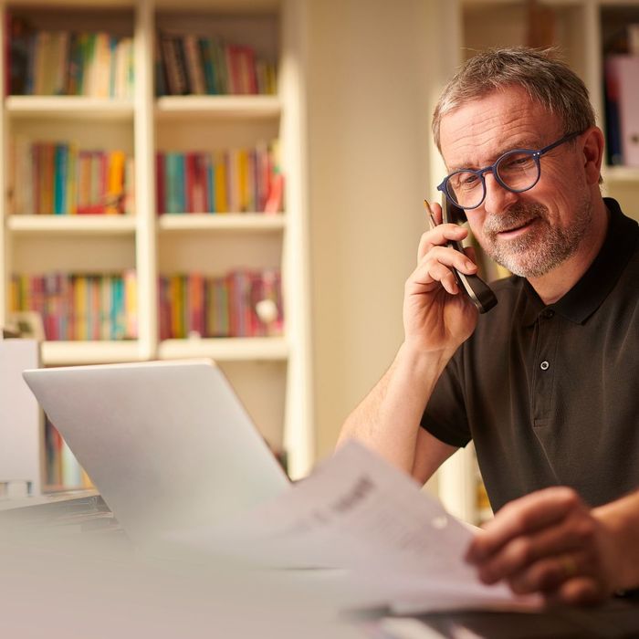 a man talking on the phone while looking over papers