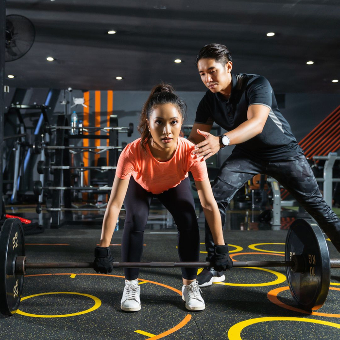 Personal trainer helping a woman complete an exercise. 